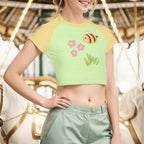 Woman wearing a green and yellow crop top with a bee design, standing in front of a carousel.