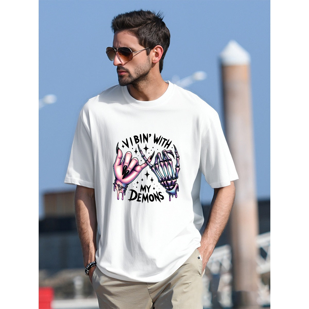 Man wearing a white t-shirt with a graphic design and text, standing outdoors.