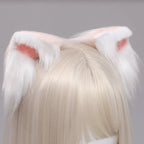 White fluffy cat ears with red accents on a person wearing a blonde wig against a gray background.