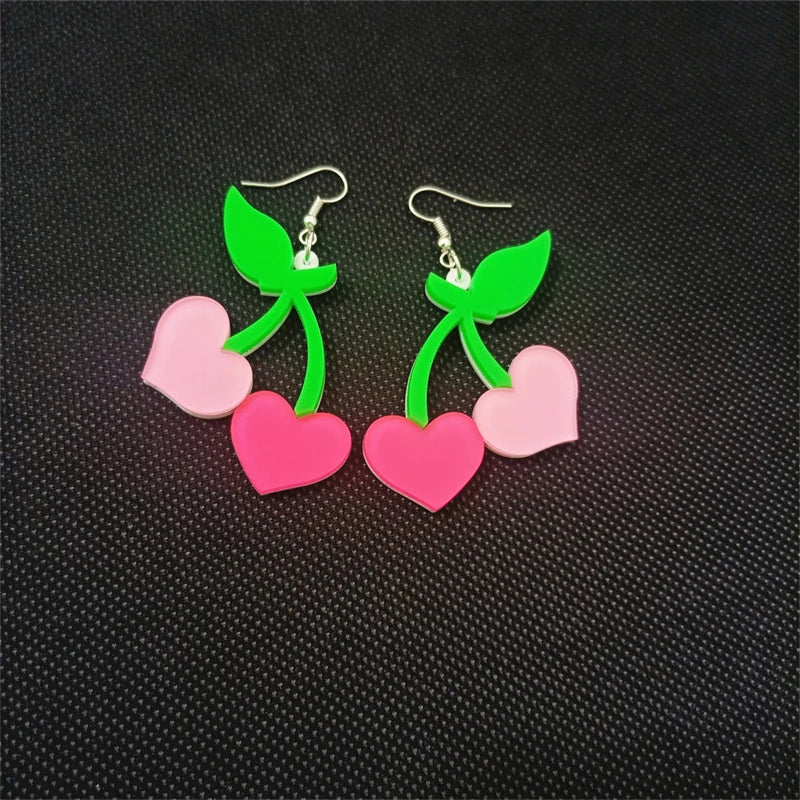 Pair of earrings with pink hearts and green stems on a black textured background