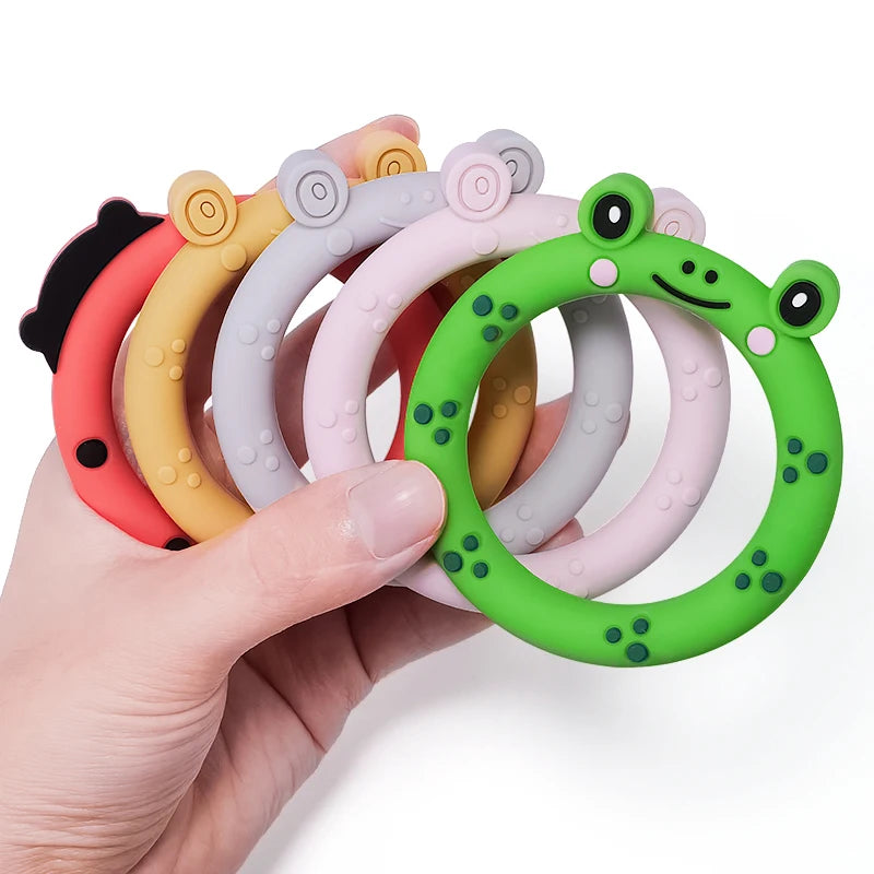 Set of colorful silicone teething rings held by a hand on a white background