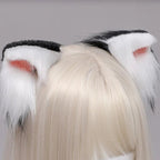 White and black cat ears with red accents on a person wearing a blonde wig against a gray background.