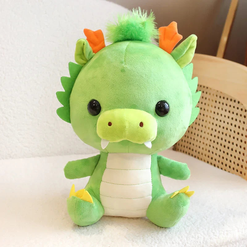 Green plush dragon toy with orange horns on a light background