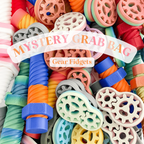 Colorful gear fidgets with a 'Mystery Grab Bag' label on a white background